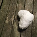 Heart made of snow on wood deck.